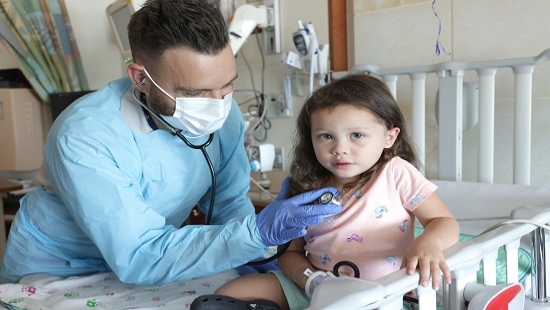 Fellow using stethoscope to check on patient